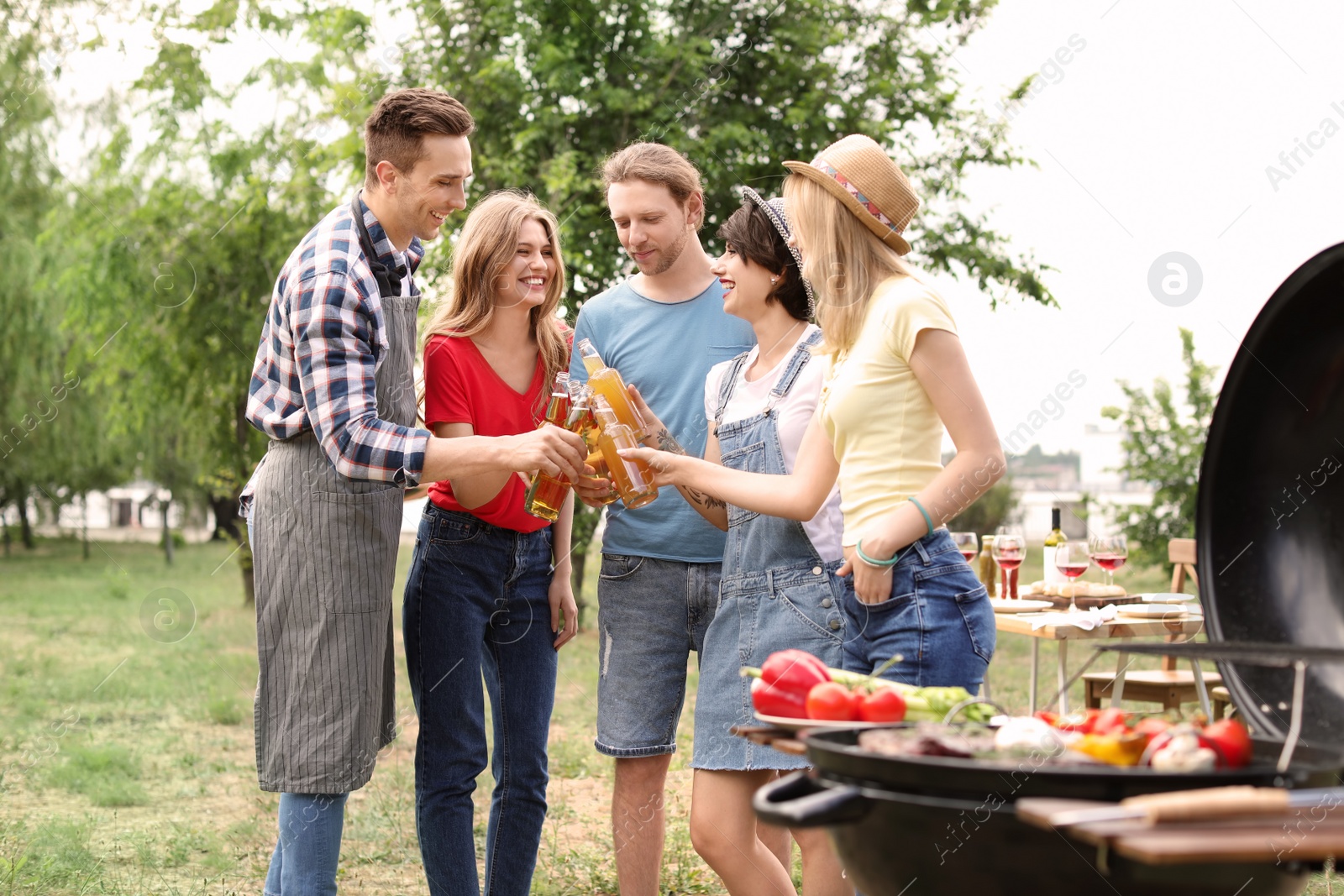 Photo of Young people having barbecue with modern grill outdoors