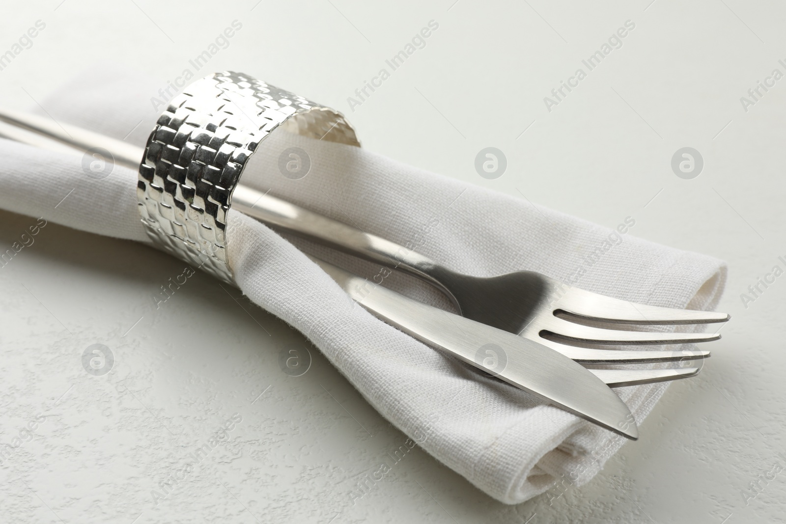 Photo of Stylish setting with cutlery and napkin on white textured table, closeup