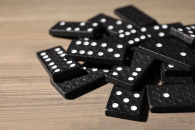 Photo of Black domino tiles on wooden table, closeup