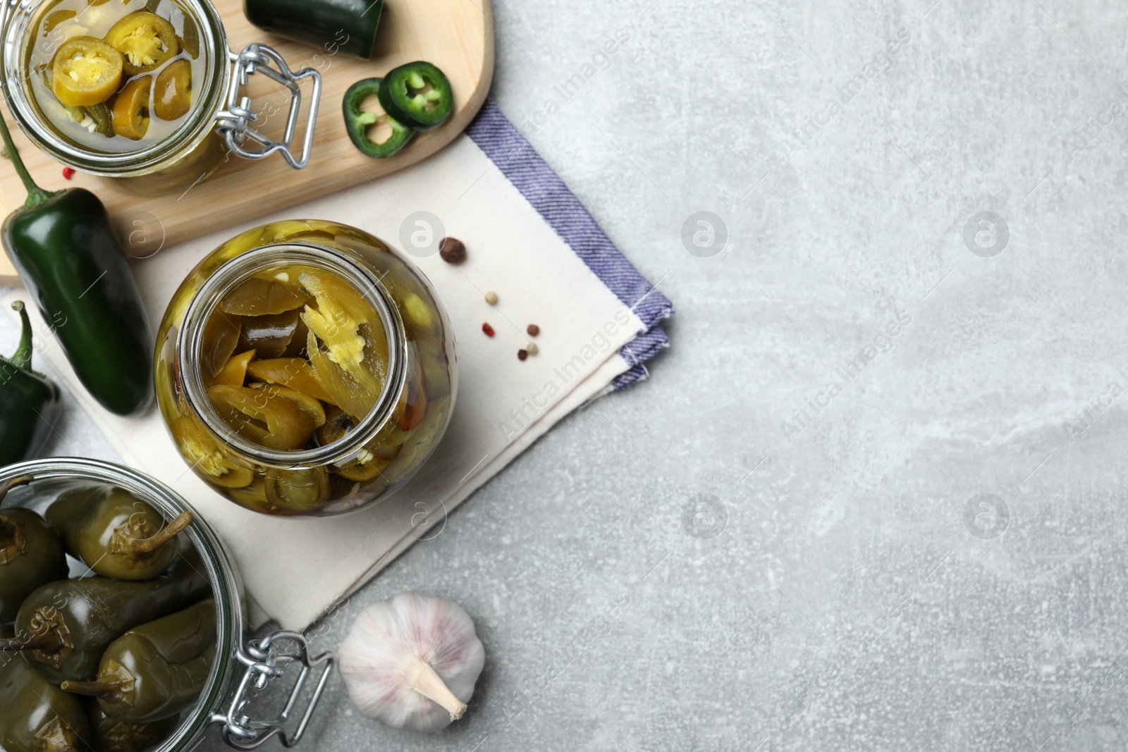 Photo of Flat lay composition with pickled green jalapeno peppers on light grey table, space for text