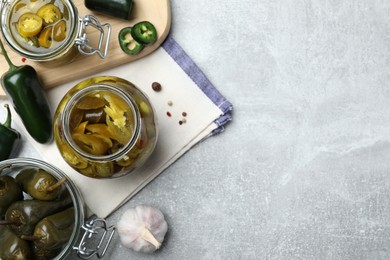 Flat lay composition with pickled green jalapeno peppers on light grey table, space for text