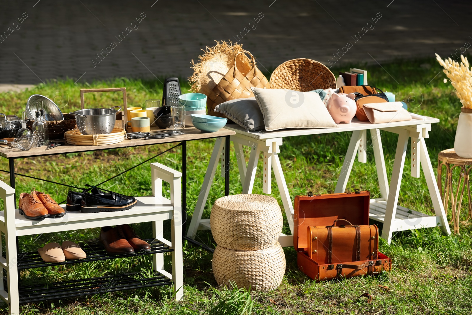 Photo of Small tables with many different items on garage sale outdoors