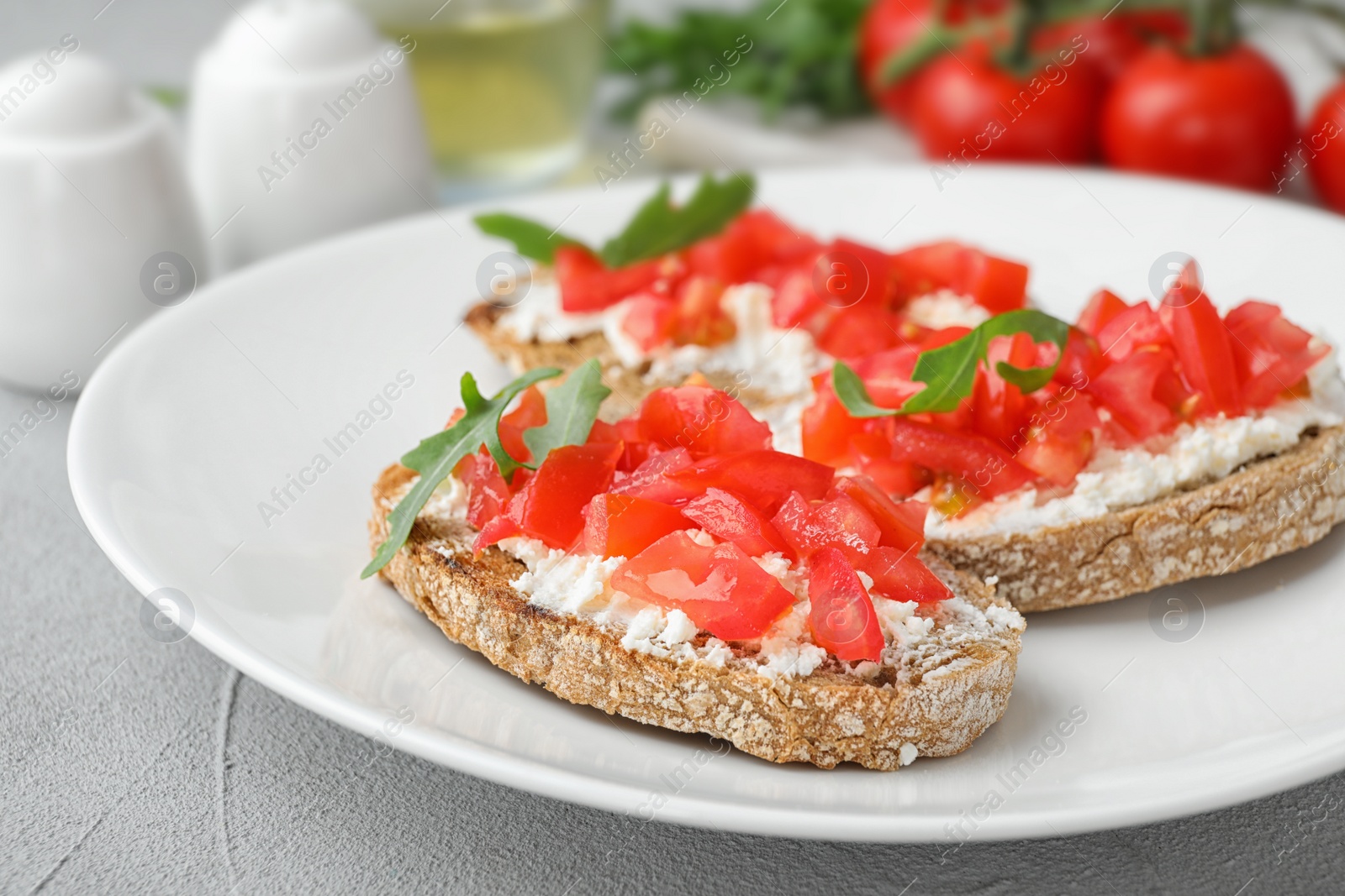 Photo of Plate of delicious tomato bruschettas on table, closeup