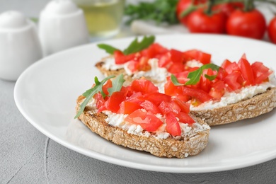 Photo of Plate of delicious tomato bruschettas on table, closeup