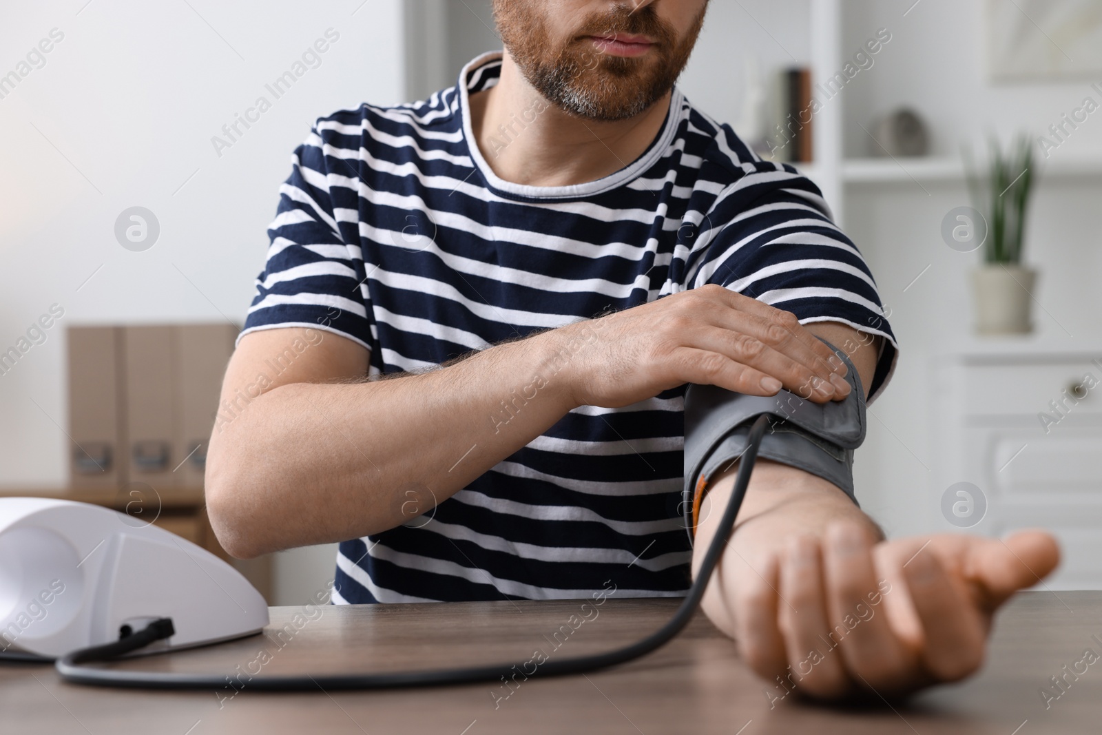 Photo of Man measuring blood pressure in room, closeup