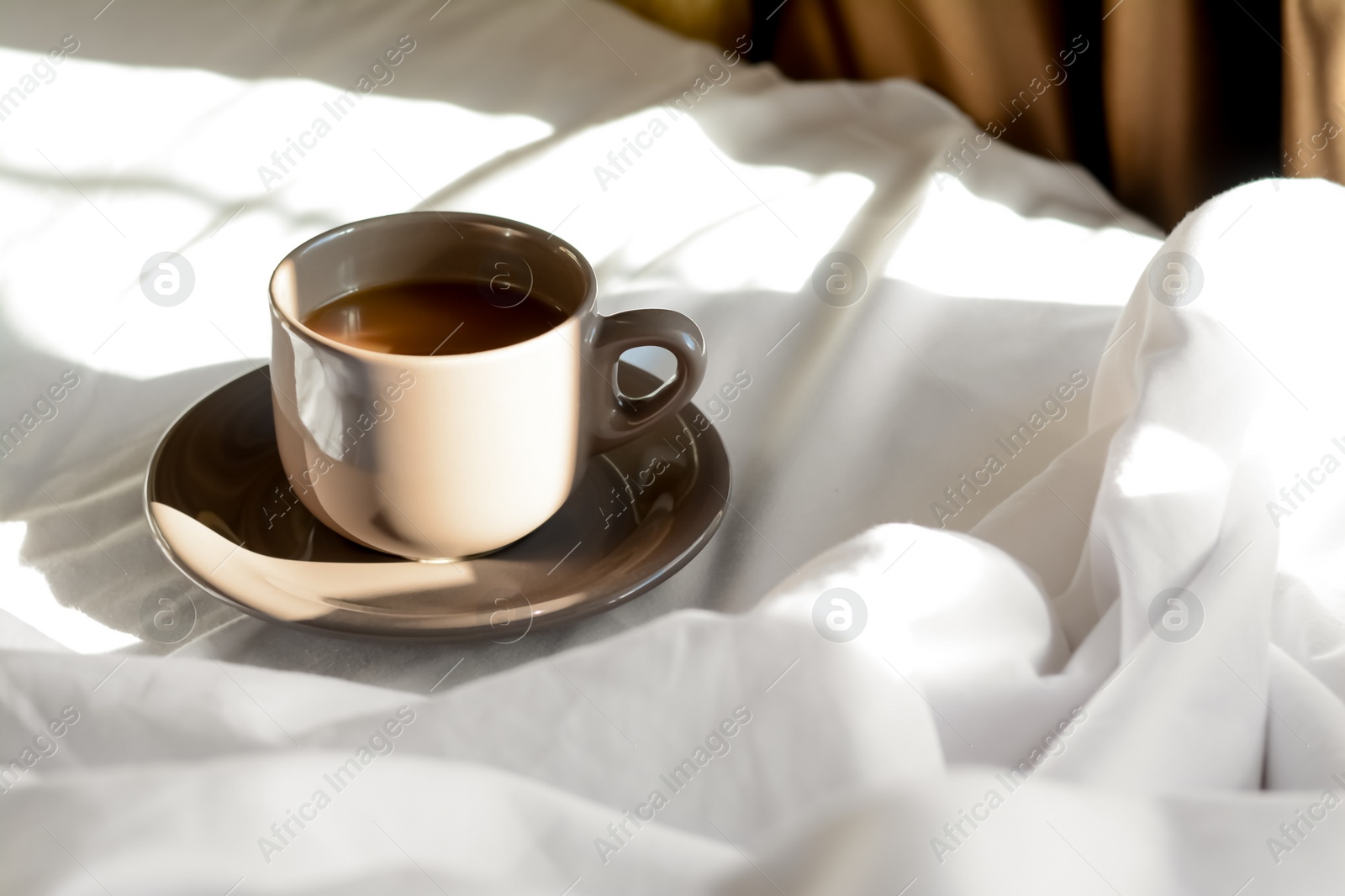 Photo of Cup of aromatic coffee on bed in morning, space for text