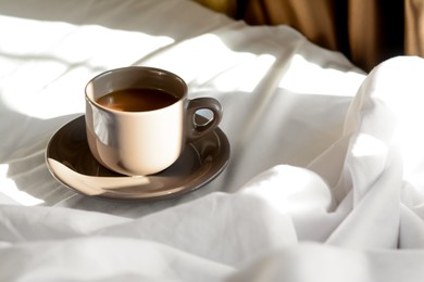 Cup of aromatic coffee on bed in morning, space for text