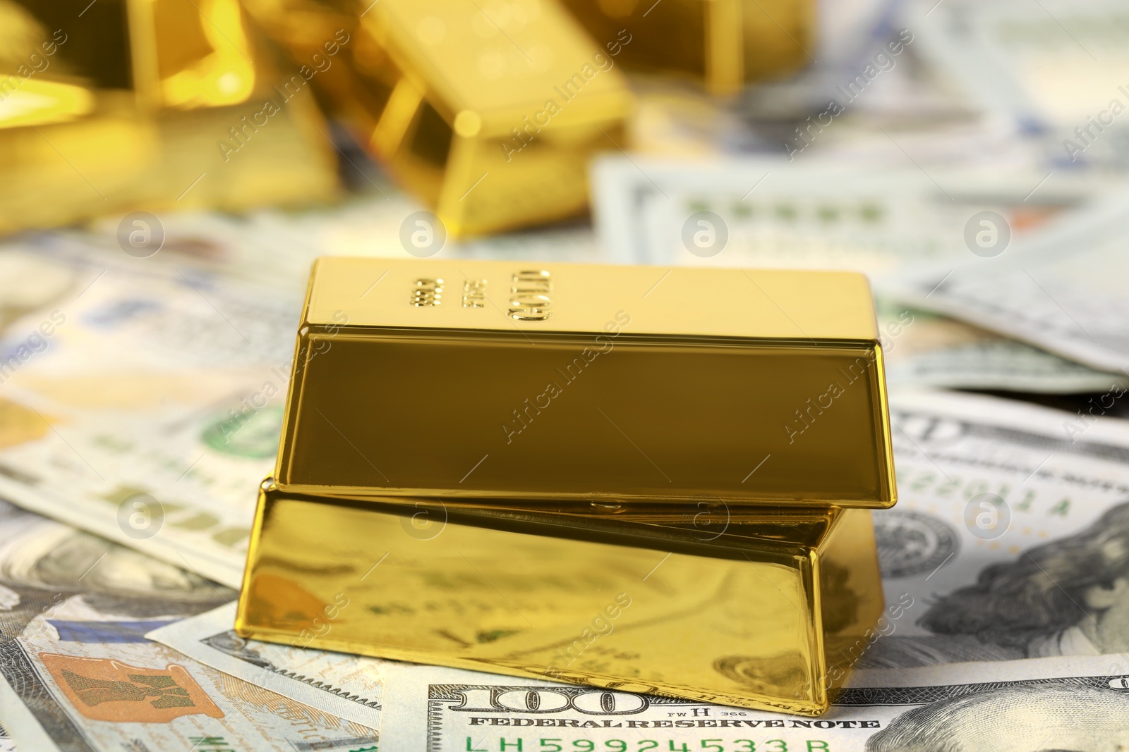 Photo of Shiny gold bars on dollar banknotes, closeup