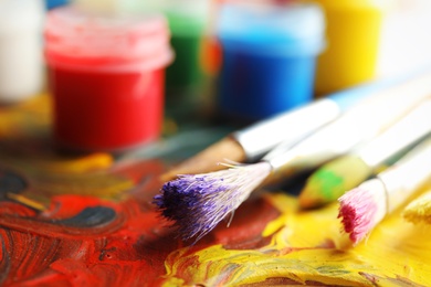 Photo of Different brushes and jars with paint on palette, closeup. Space for text