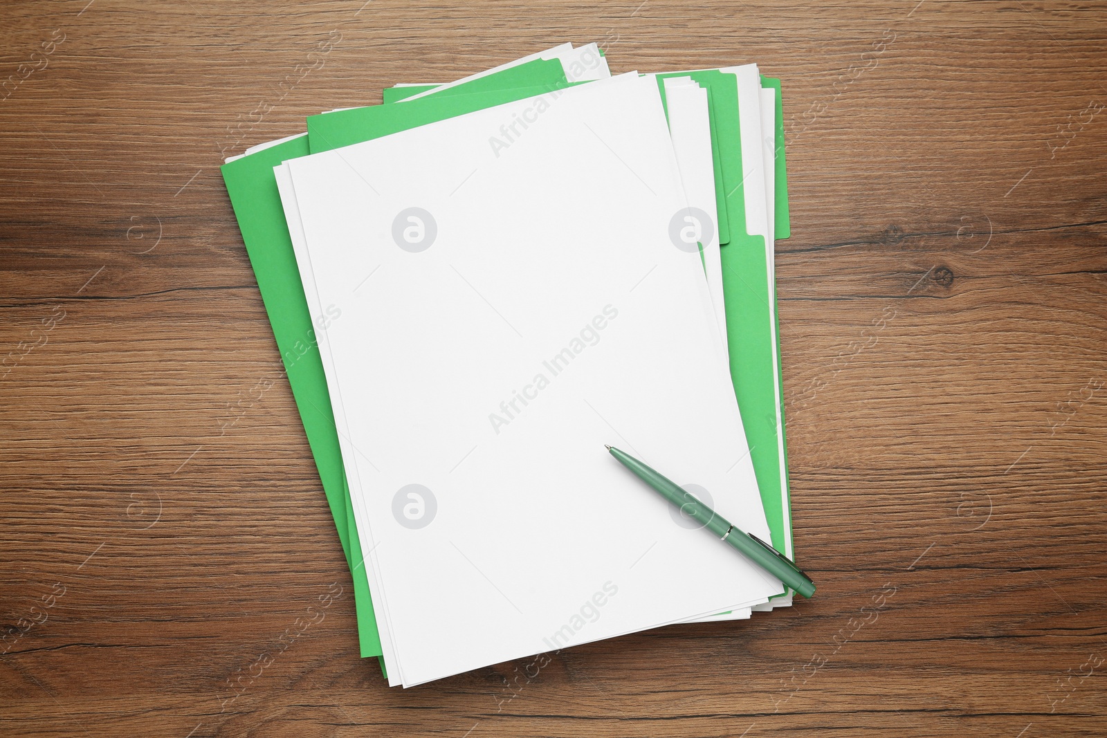 Photo of Light green files with blank sheets of paper and pen on wooden table, top view. Space for design