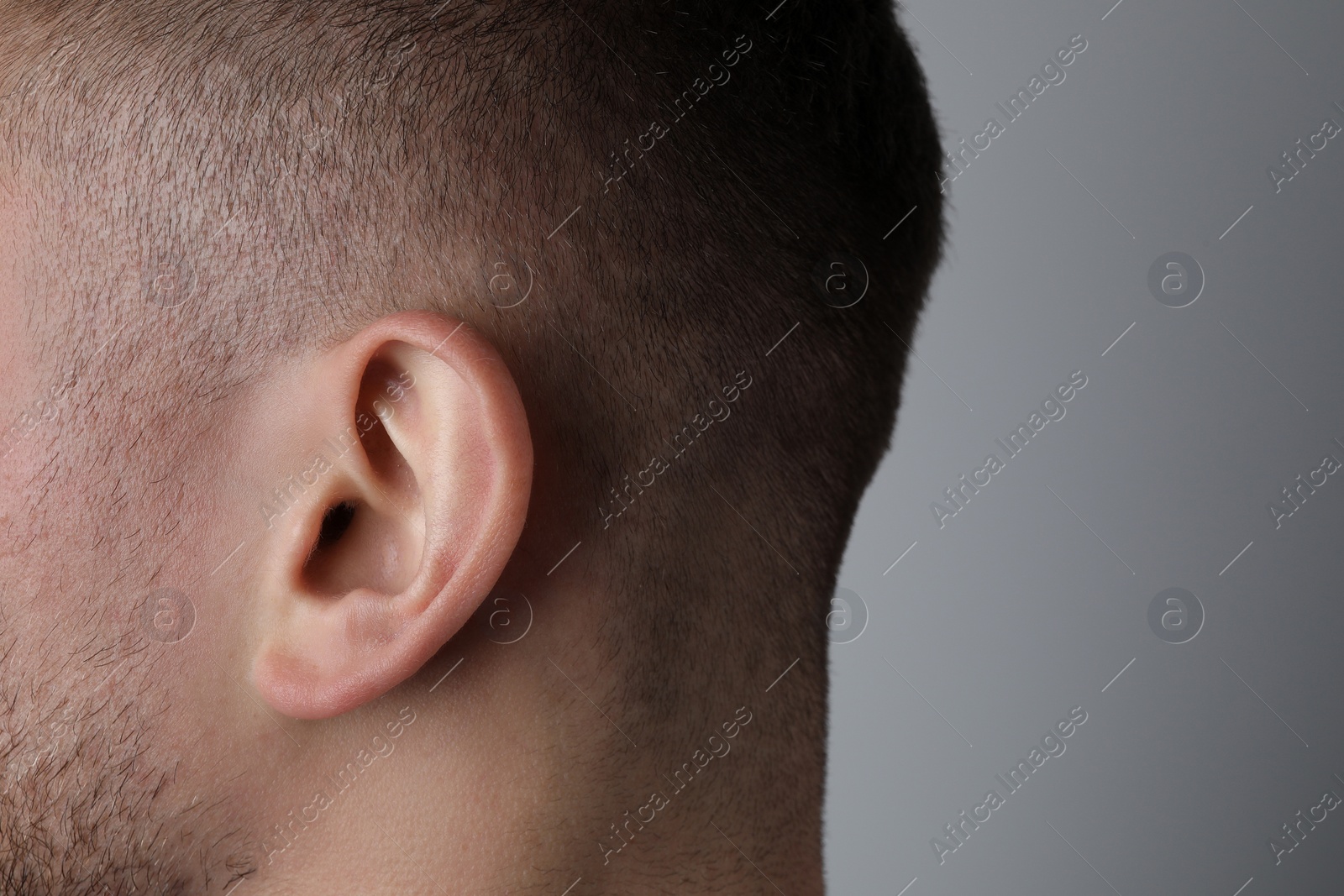 Photo of Man on grey background, closeup of ear