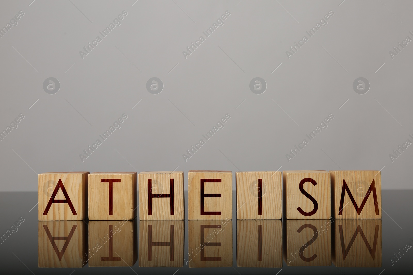 Image of Word Atheism made of wooden cubes with letters on mirror surface