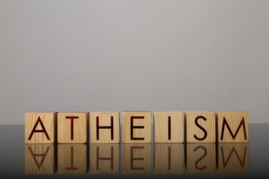 Word Atheism made of wooden cubes with letters on mirror surface