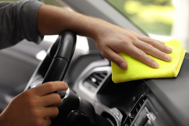 Man cleaning car interior with rag, closeup