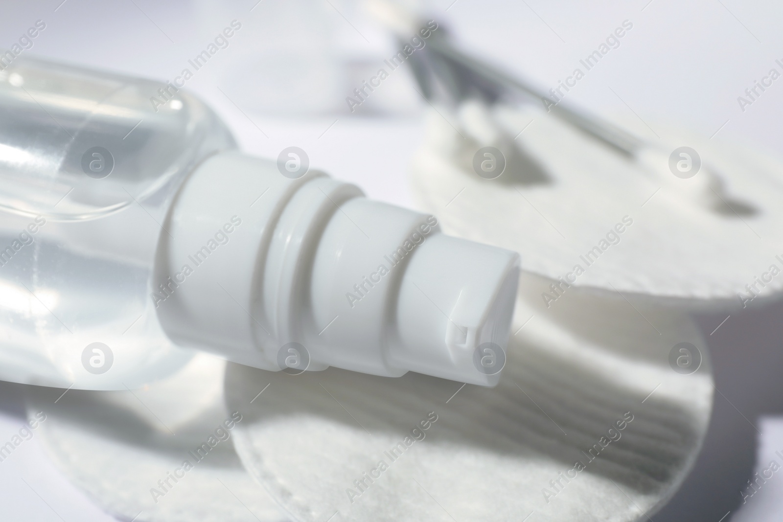 Photo of Bottle of micellar water, cotton pads and swabs on white table, closeup