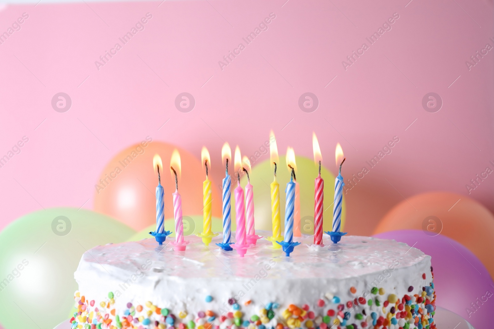 Photo of Birthday cake with burning candles and balloons on color background. Space for text