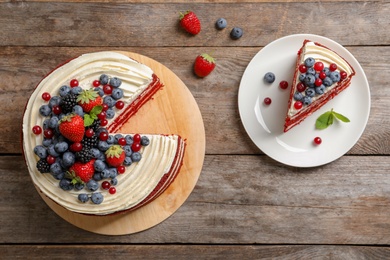 Delicious homemade red velvet cake with fresh berries on wooden table, top view