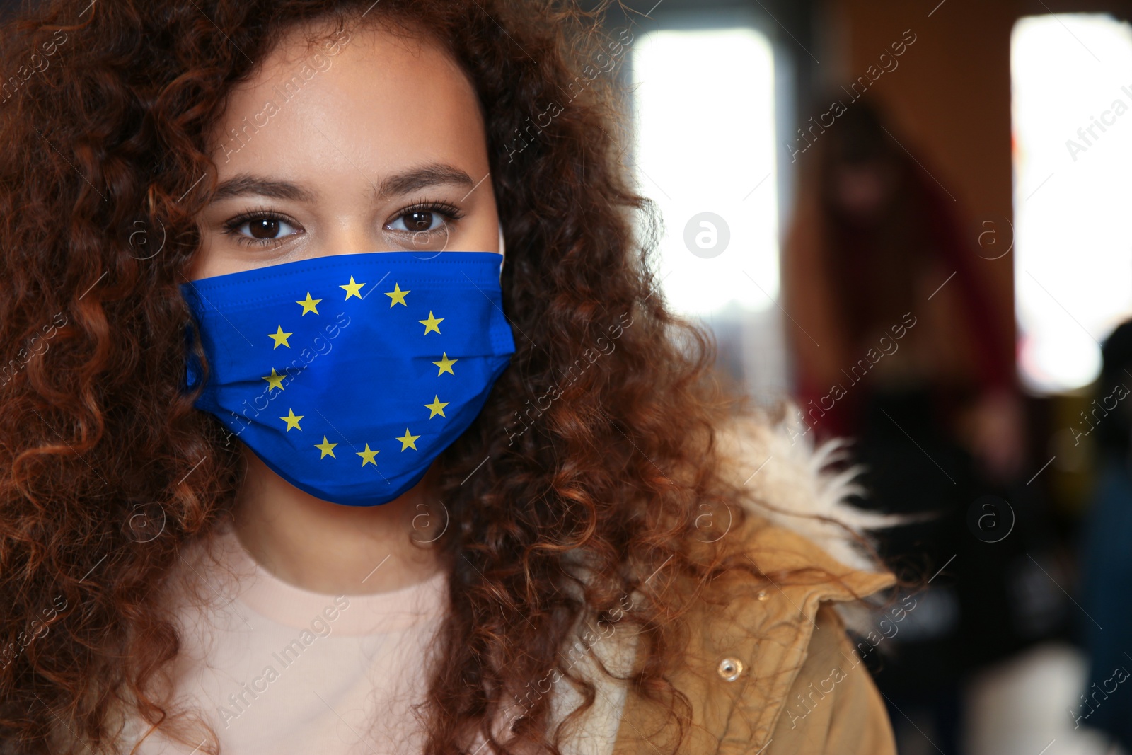 Image of African American woman wearing medical mask with European Union flag, outdoors. Coronavirus outbreak in Europe