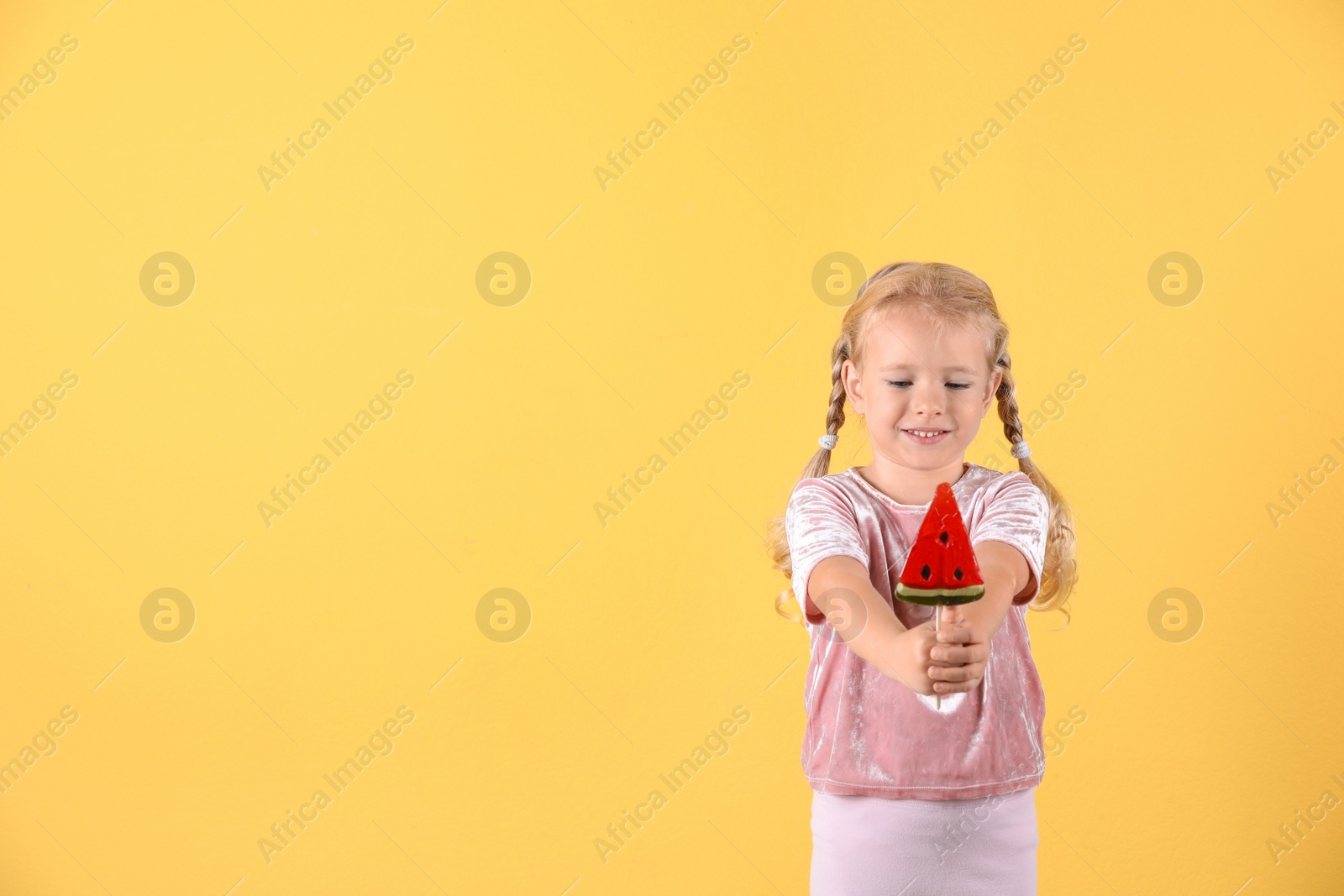 Photo of Cute little girl with candy on color background. Space for text