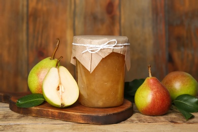 Photo of Delicious pear jam and fresh fruits on wooden table