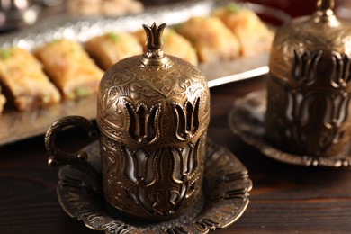 Photo of Traditional Turkish tea and fresh baklava served in vintage tea set on wooden table, closeup