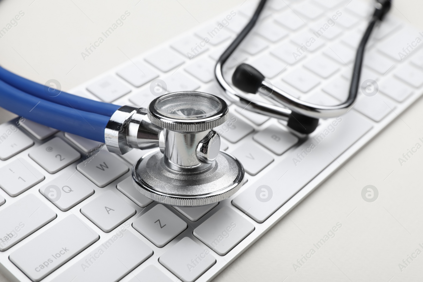 Photo of Keyboard and stethoscope on beige background, closeup