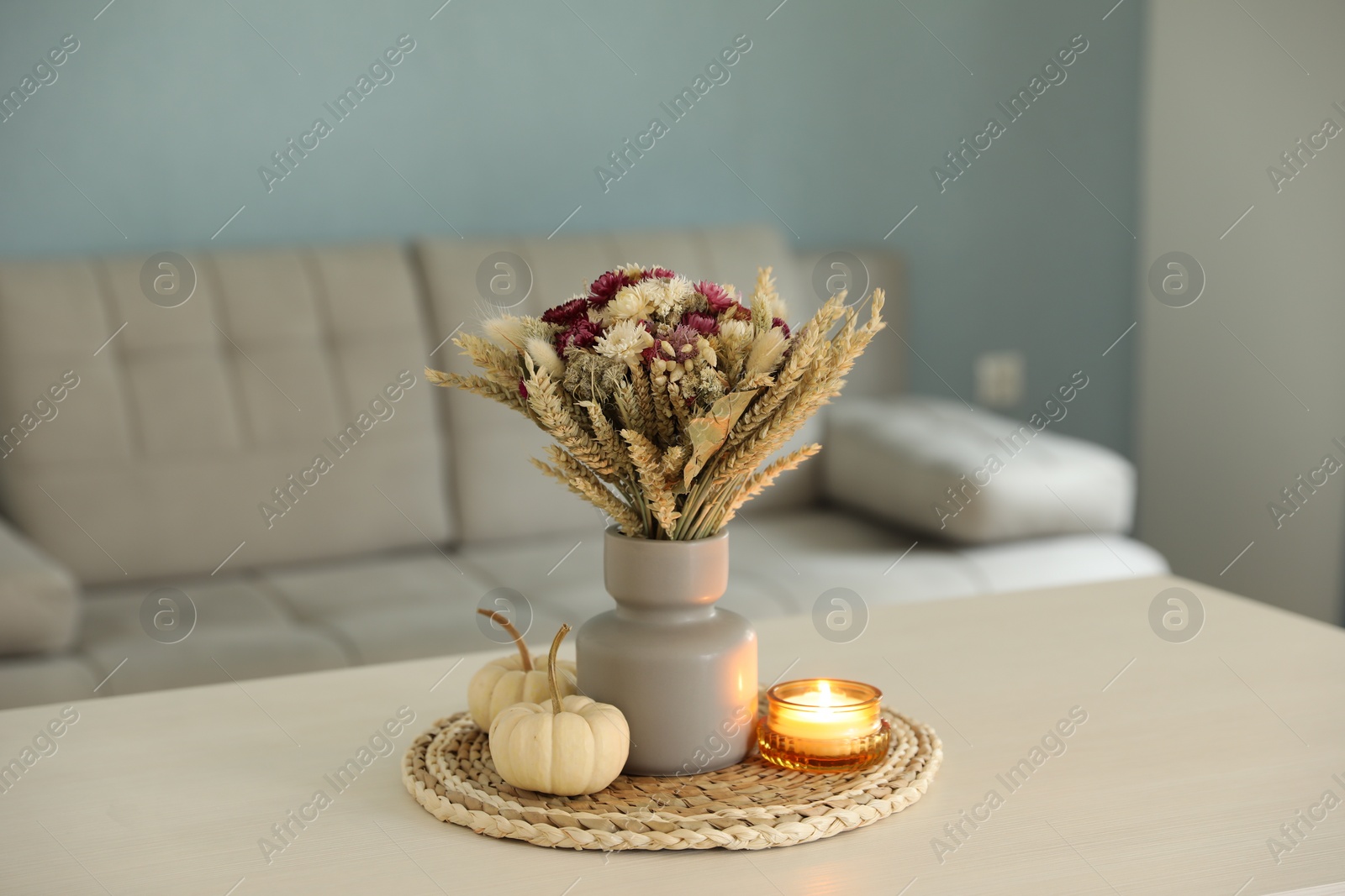 Photo of Beautiful bouquet of dry flowers, small pumpkins and candle on white table indoors