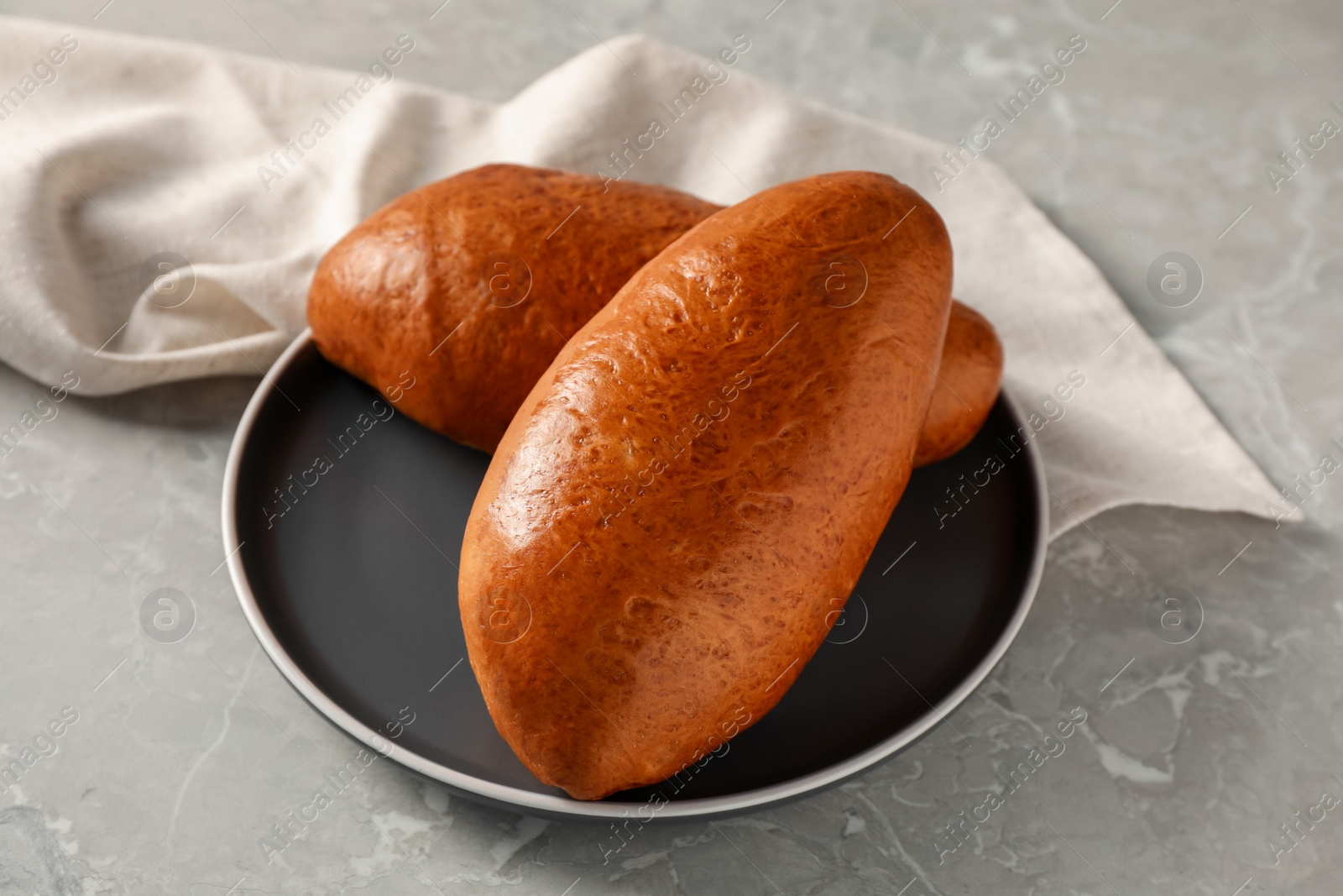 Photo of Tasty freshly baked pirozhki on light grey marble table, closeup