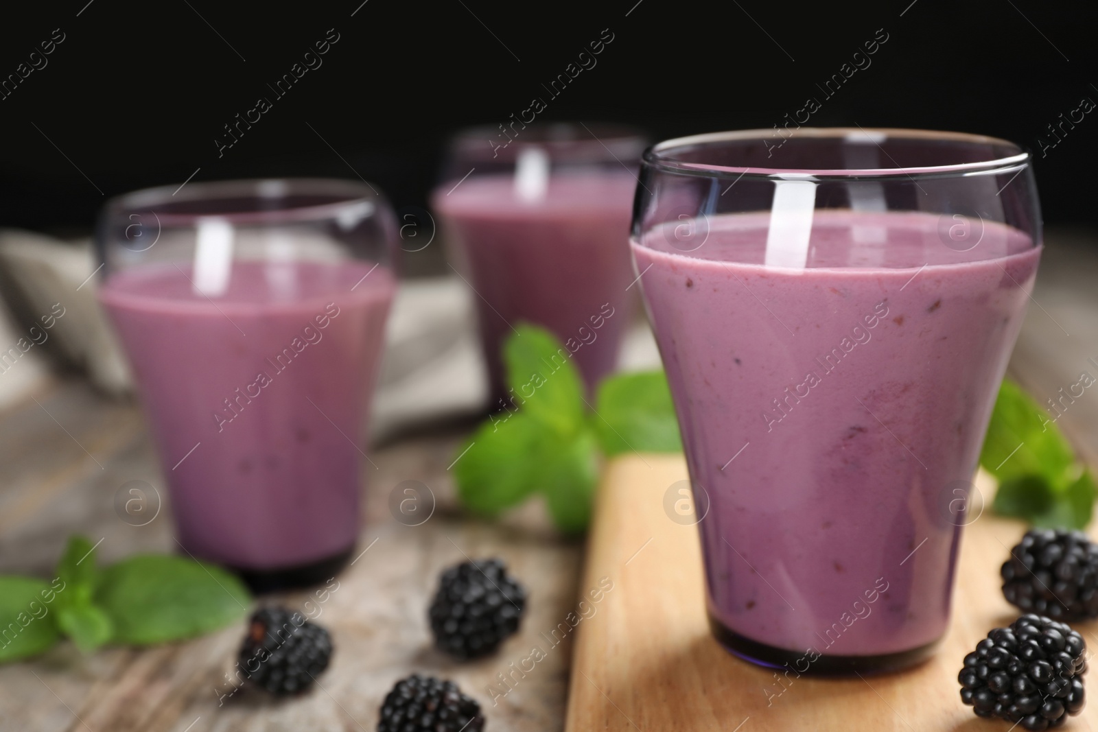 Photo of Glasses with tasty blackberry yogurt smoothies on table