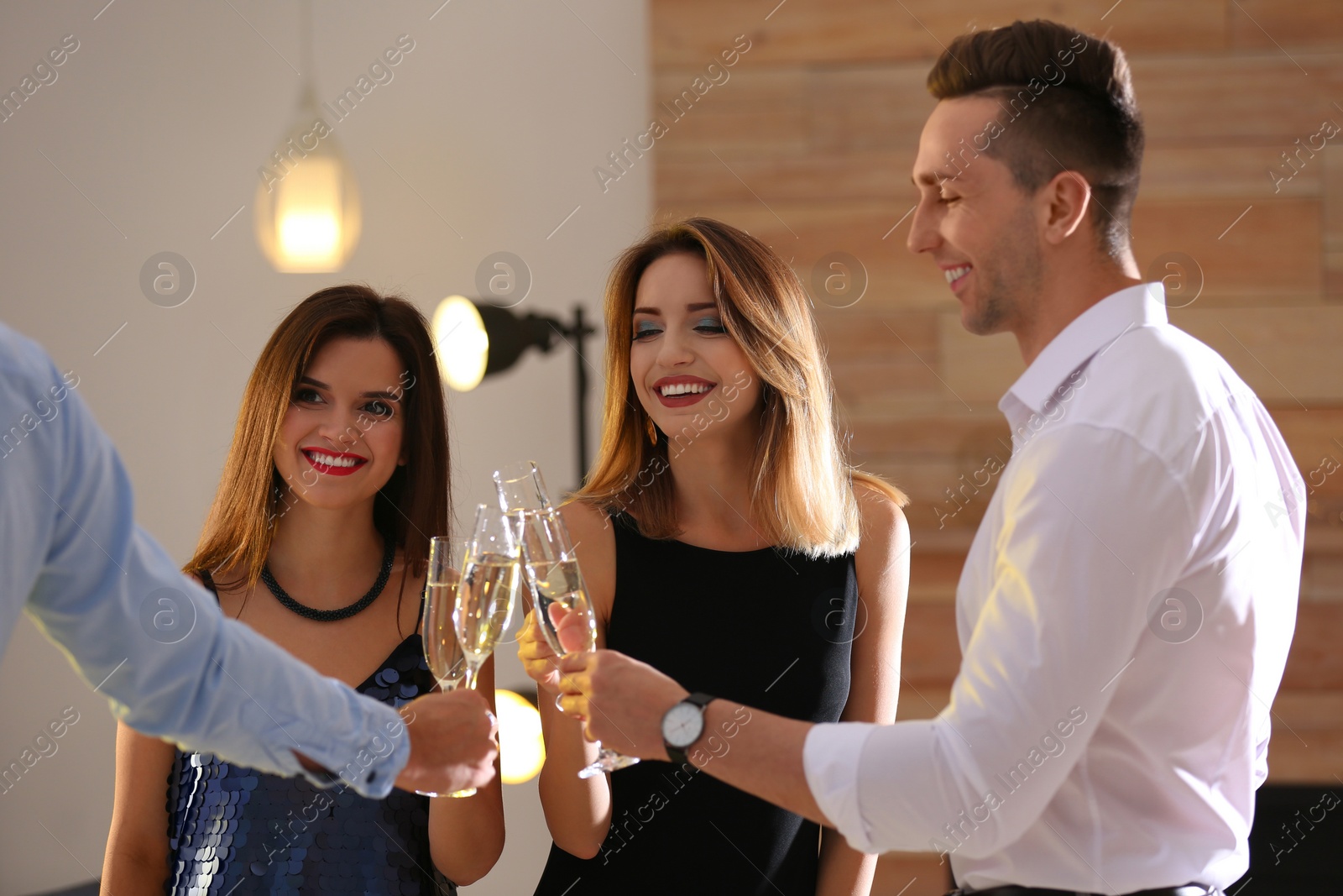 Photo of Friends clinking glasses with champagne at party indoors