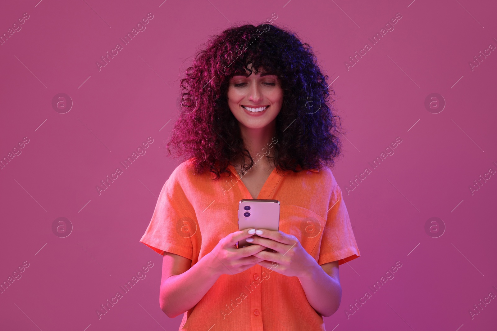 Photo of Woman sending message via smartphone on pink background