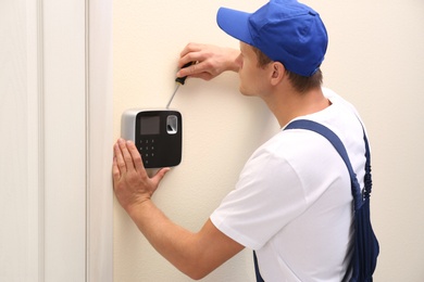 Male technician installing security alarm system indoors