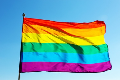 Rainbow LGBT flag fluttering on blue sky background. Gay rights movement