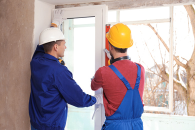 Photo of Workers using bubble level for installing window indoors