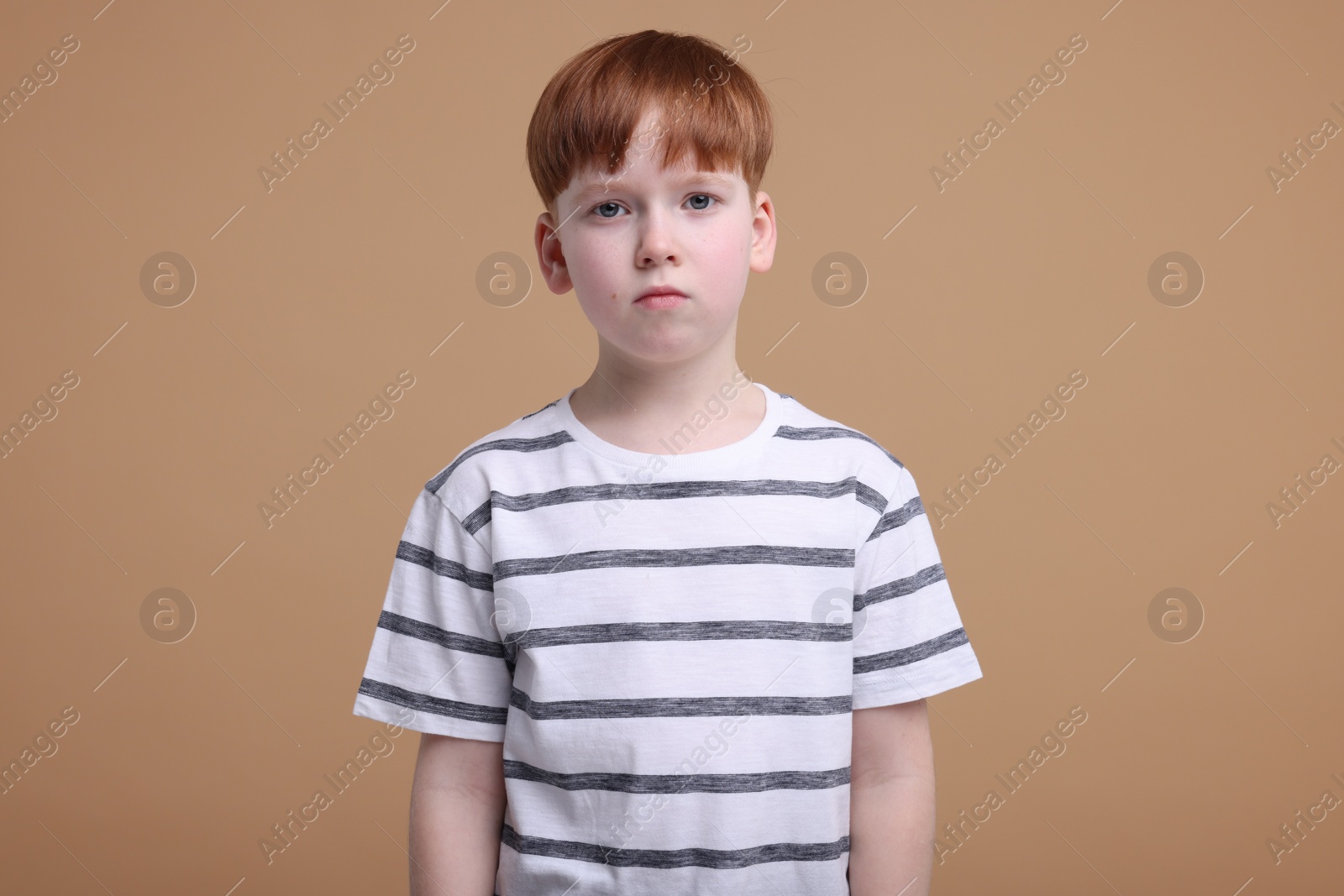 Photo of Portrait of sad little boy on beige background