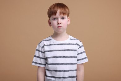 Photo of Portrait of sad little boy on beige background