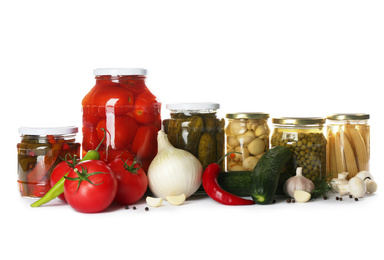 Glass jars with different pickled vegetables and mushrooms on white background