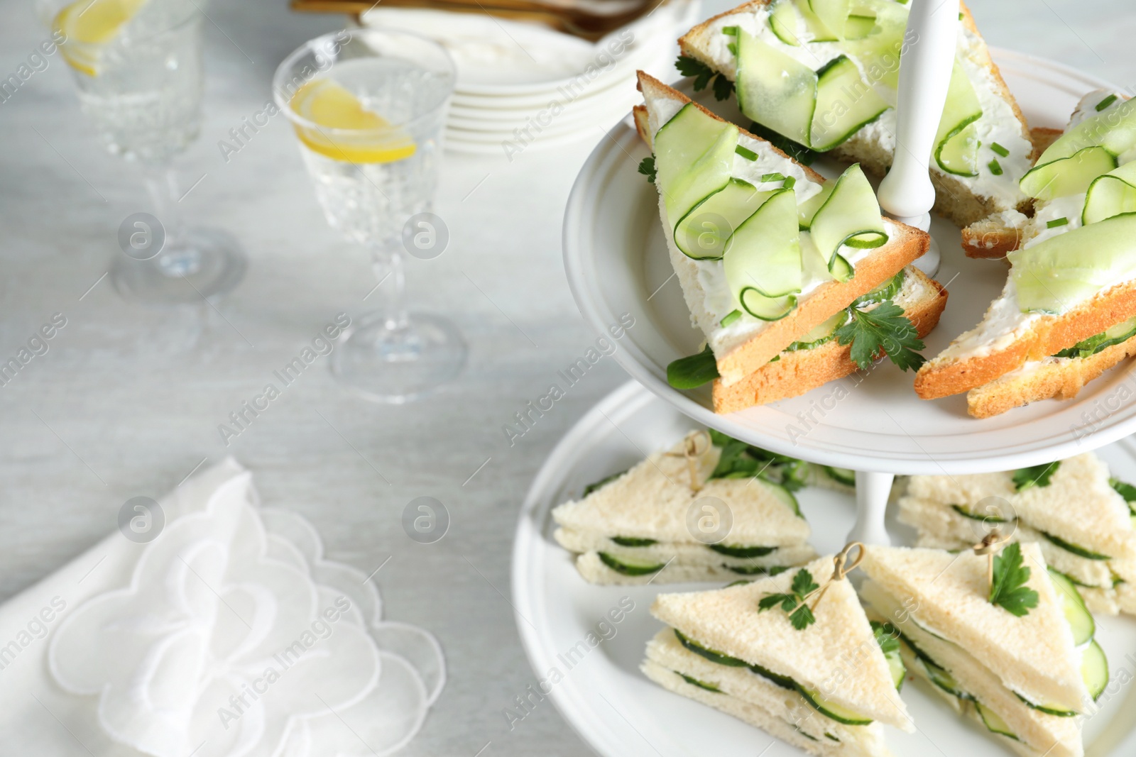 Photo of Stand with traditional English cucumber sandwiches on table. Space for text