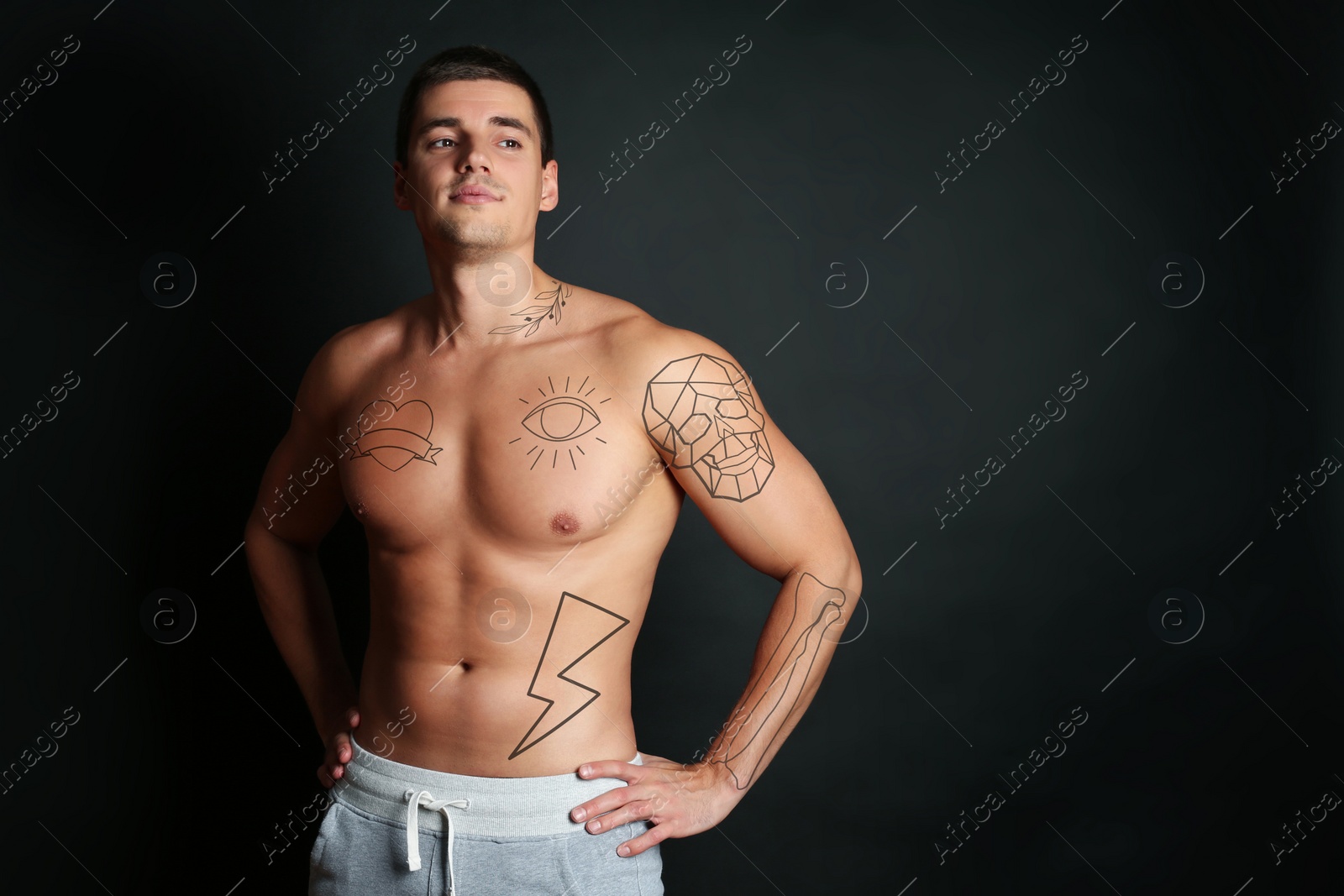 Image of Handsome man with beautiful tattoo sketches on black background. Space for text