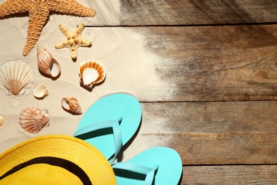 Flat lay composition with beach objects, sand and space for text on wooden background