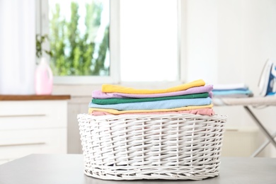 Basket with clean laundry on table at home