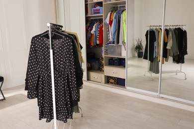 Rack with stylish women's clothes in dressing room