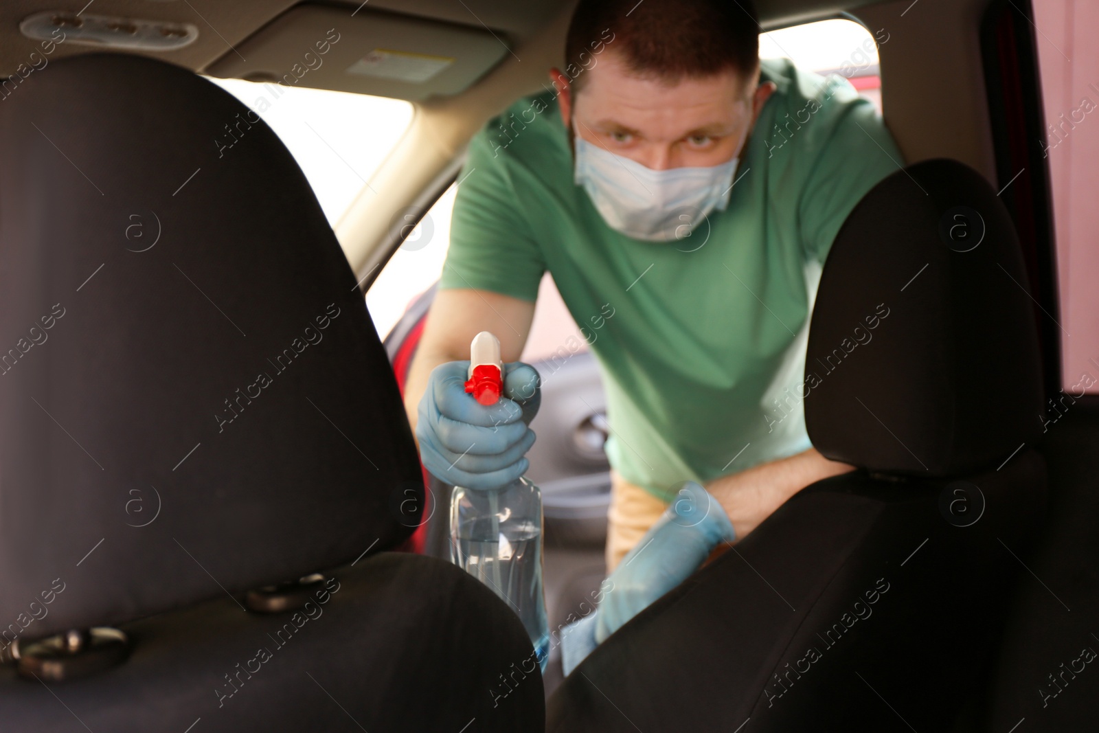 Photo of Man cleaning car salon with disinfectant spray