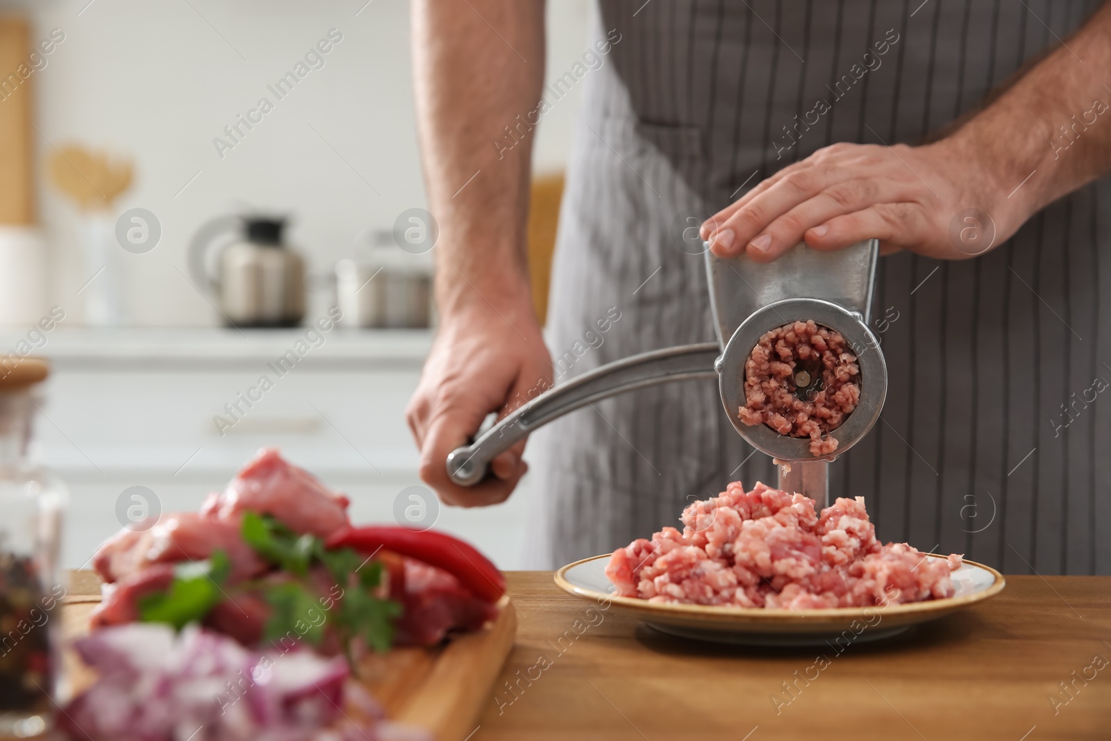 Photo of Man using hand meat grinder in kitchen, closeup