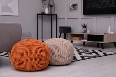 Photo of Two stylish knitted poufs on floor in living room