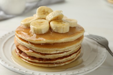 Photo of Delicious pancakes with bananas and honey on white table, closeup