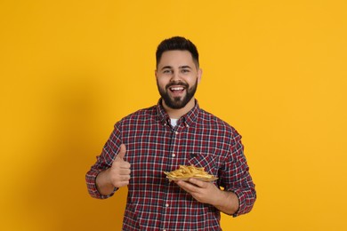 Photo of Young man with French fries on orange background