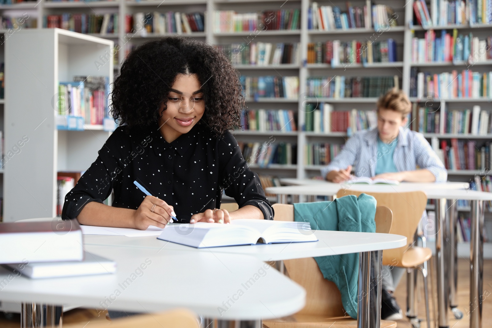 Photo of Young African-American woman studying at table in library