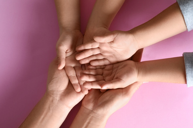Photo of Happy family holding hands on pink background, top view