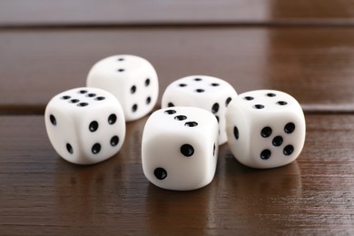 Photo of Many white game dices on wooden table, closeup